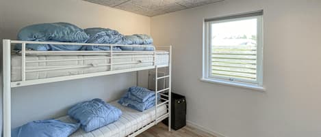 Dormitorio con literas, ventana y ventilador de techo.