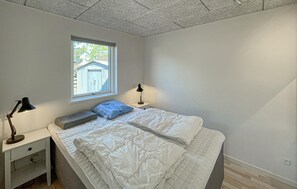 Ein Schlafzimmer mit einem Bett, zwei Nachttischen, einem Fenster und einer Decke mit strukturierter Musterung.