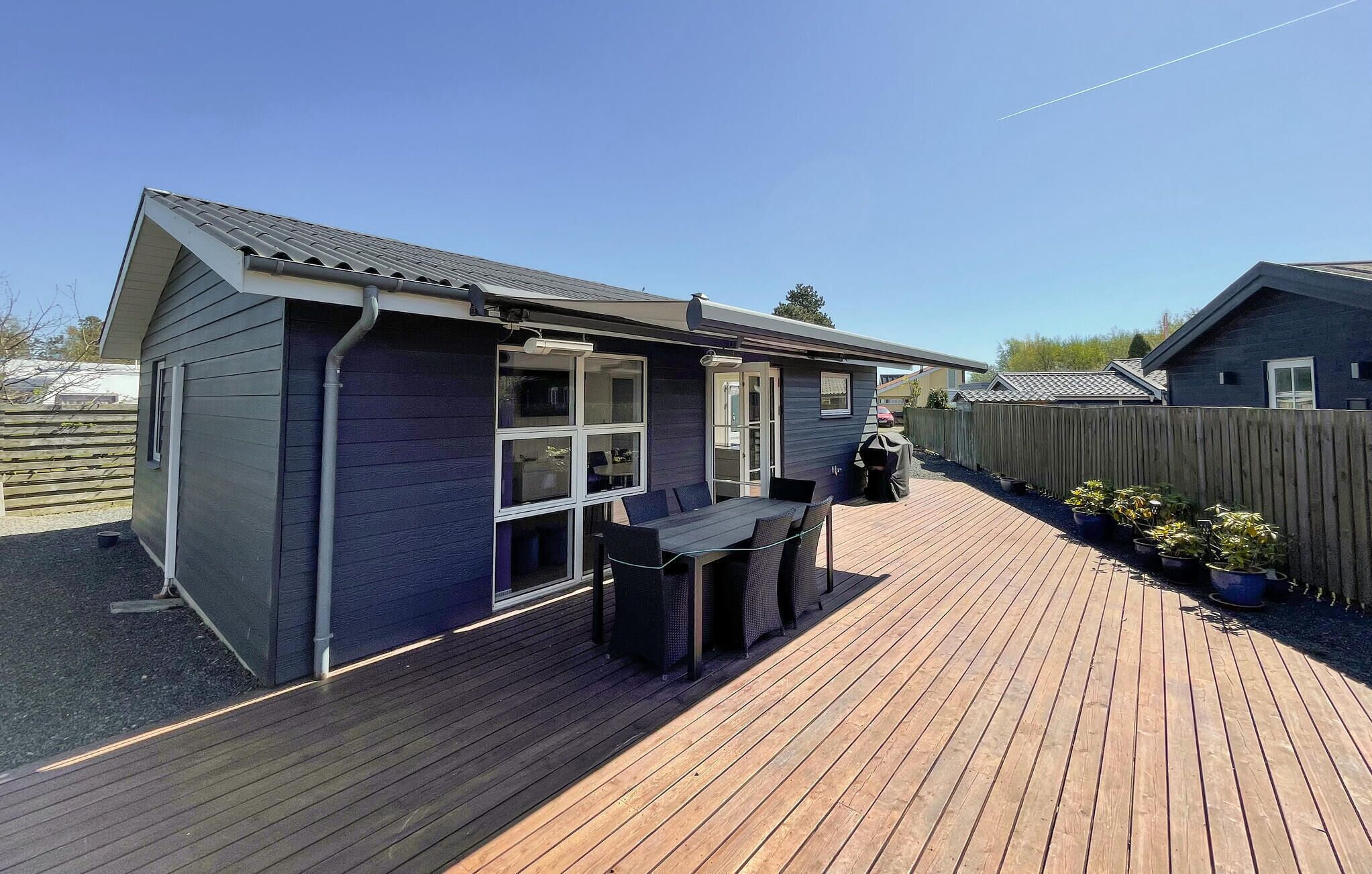 A house with a deck, a covered outdoor area, and a fenced backyard.