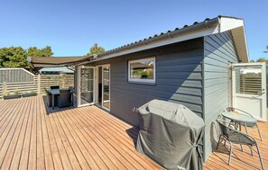 Eine überdachte Terrasse mit Grill, einem Fenster und einer Tür zu einem überdachten Patio-Bereich.