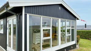 Une maison dotée d’une grande baie vitrée, d’une terrasse en bois et d’un drapeau sur le toit.