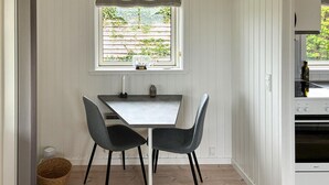 Une cuisine avec une table et des chaises, une fenêtre donnant sur un espace verdoyant et une cuisinière.