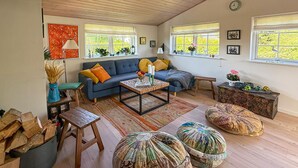 Un salon chaleureux avec un canapé, une table basse, des poufs et un banc en bois.
