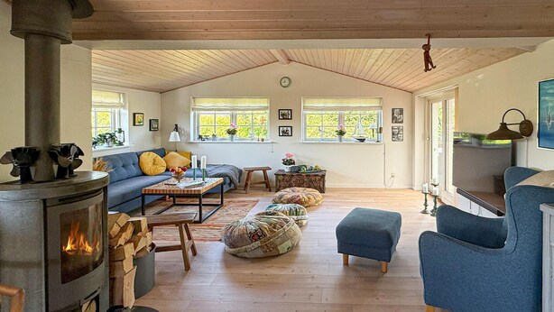 Un salon chaleureux avec une cheminée, un canapé, des poufs et un téléviseur.