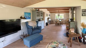 Un salon chaleureux avec un canapé bleu, un téléviseur à écran plat, une table à manger en bois avec des chaises et une cheminée.