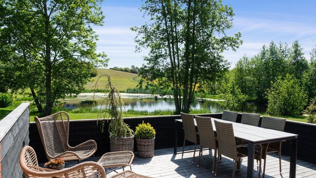 En terrasse med flettmøbler, et bord og plantekrukker.
