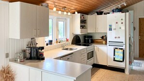 A modern kitchen with white cabinets, a central island, a built-in oven, and a refrigerator. - Awesome home in Farsø with sauna (Farsø)