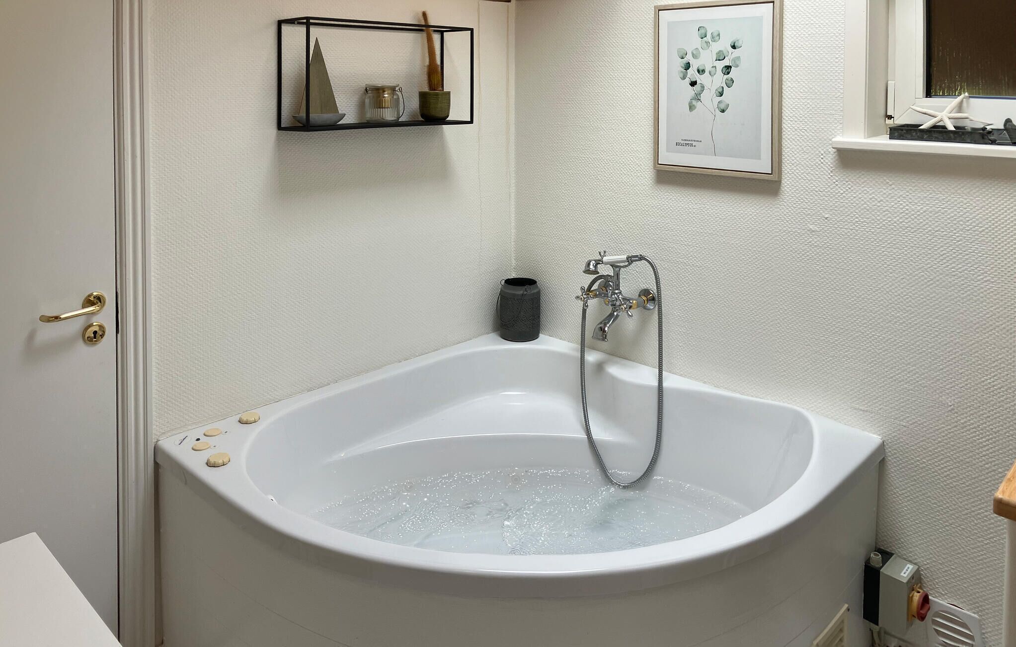 A bathroom with a bathtub, a shower, and a small shelf with decorative items.