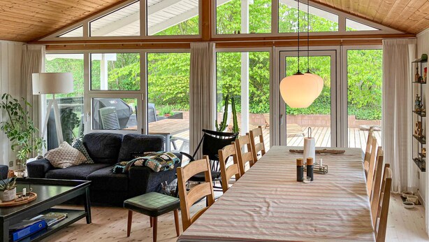 A spacious living area with a large window, a sofa, a dining table, and a hanging light fixture. - Awesome home in Farsø with sauna (Farsø)