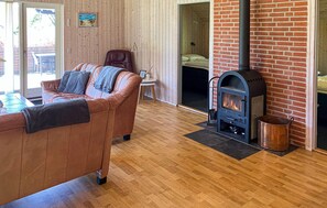 A cozy living room with a leather sofa, a fireplace, and a wooden floor. - 4 bedroom gorgeous home in Farsø (Farsø)