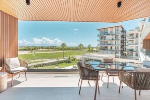 Ein Balkon mit Glastisch und Stühlen mit Blick auf ein Wohngebiet mit Gebäuden und Grünflächen.