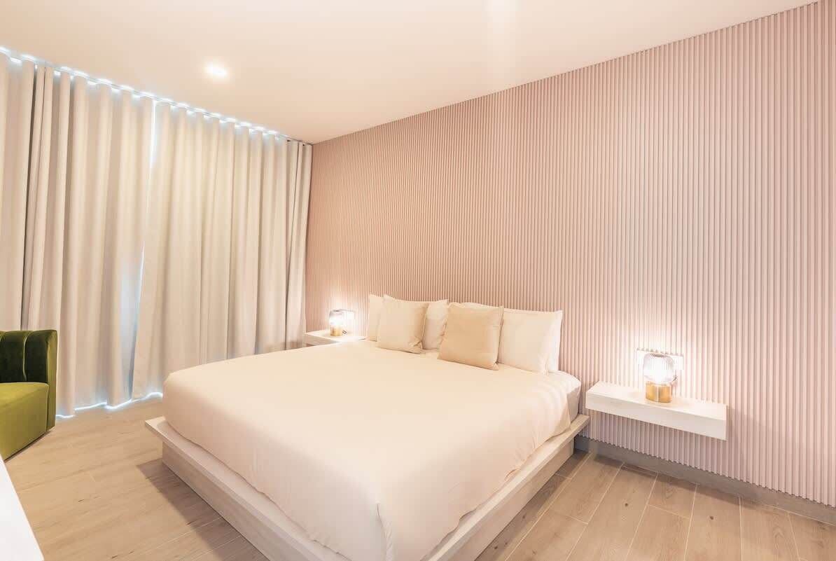 Ein modernes Schlafzimmer mit einem großen Bett, einem grünen Sessel und einem Nachttisch mit einer Lampe.