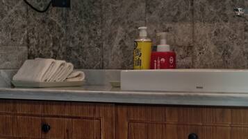 A bathroom with a marble wall, wooden cabinets, a towel rack, and a scale.