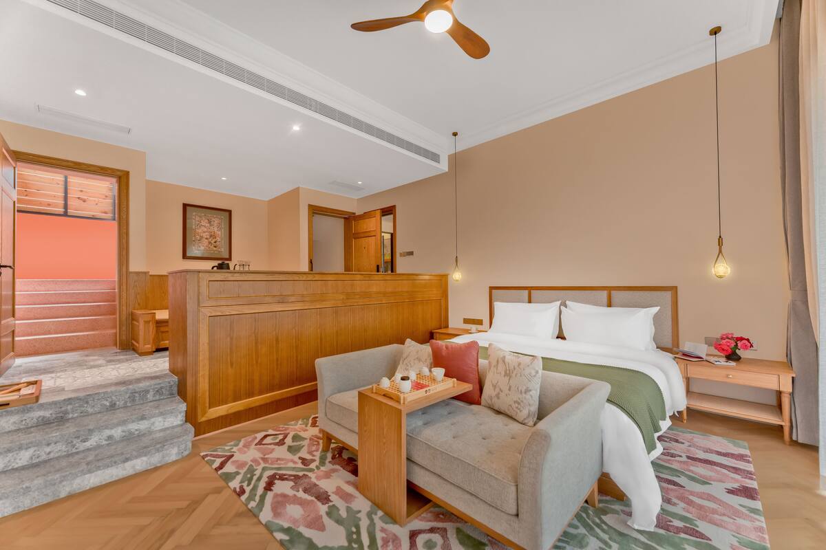 Une chambre d’hôtel comprenant un lit, un canapé, un bureau, un ventilateur de plafond et un escalier.