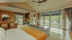 Habitación de hotel con una cama grande, un escritorio, un sofá y vistas al exterior.