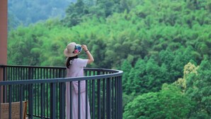Una persona en un balcón con vistas a una zona boscosa.