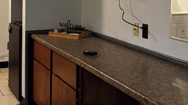 Una cocina con televisión integrada, encimera de madera y un letrero de bienvenida.