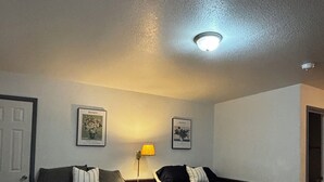 Una habitación con dos camas, una puerta, una lámpara fijada a la pared y dos cuadros enmarcados.