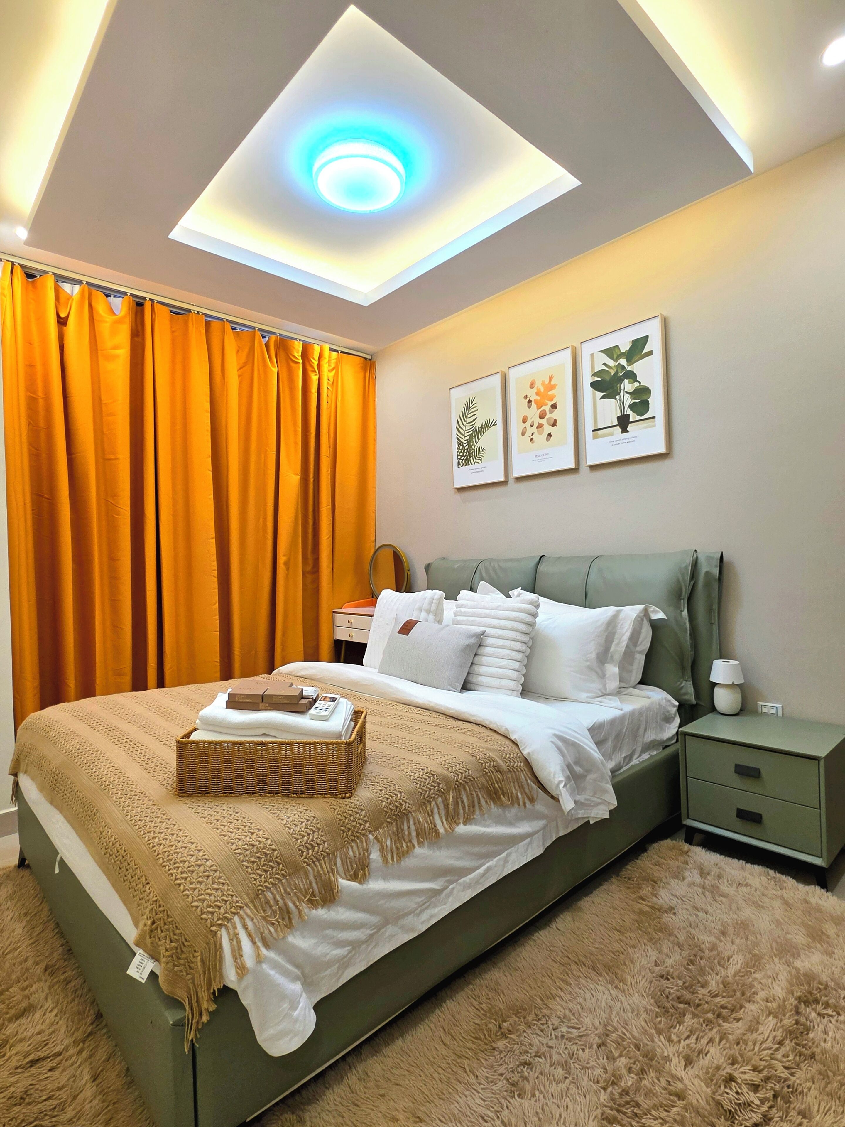 Un dormitorio con cama, mesita de noche, repisa en la pared y luz de techo.