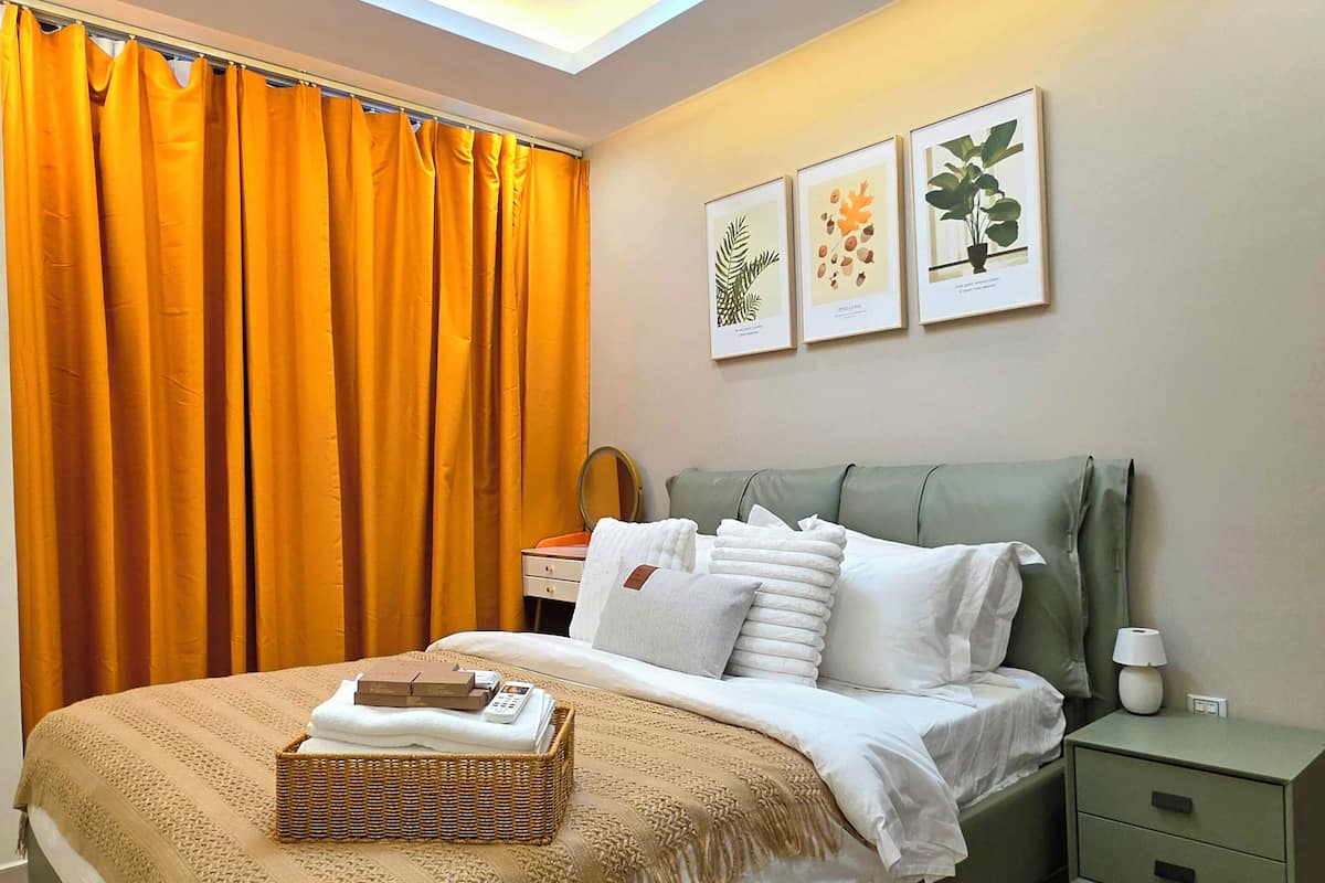 Un dormitorio con cama, mesita de noche, repisa en la pared y luz de techo.