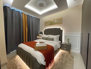 Un dormitorio moderno con cama, mesitas de noche, una lámpara de techo y una ventana con cortinas.