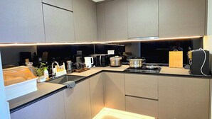 A modern kitchen with built-in appliances, a countertop, and a backsplash. - The Peak Residence by Torent Property (Phnom Penh)