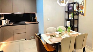 A modern kitchen with a dining area, including a table with chairs, a bookshelf, and an air conditioning unit. - The Peak Residence by Torent Property (Phnom Penh)