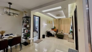 A modern living room with a dining area, a bookshelf, a sofa, and a TV. - The Peak Residence by Torent Property (Phnom Penh)