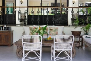 A room with a sofa, two white wicker chairs, a wooden coffee table, and a decorative plant. - 3BDR Villa Baruna, Good Location (Seminyak)