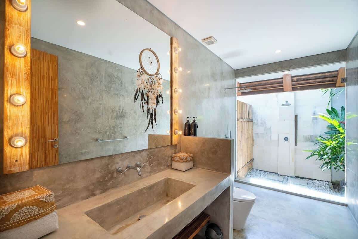A modern bathroom with a large mirror, vanity, and a dreamcatcher decoration.
