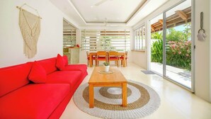 A modern living room with a red sofa, a wooden coffee table, and a ceiling fan. - Sweet Villa Love Umalas! Breakfast included (Umalas)