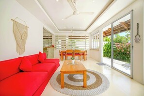 A modern living room with a red sofa, a wooden coffee table, and a ceiling fan. - Sweet Villa Love Umalas! Breakfast included (Umalas)