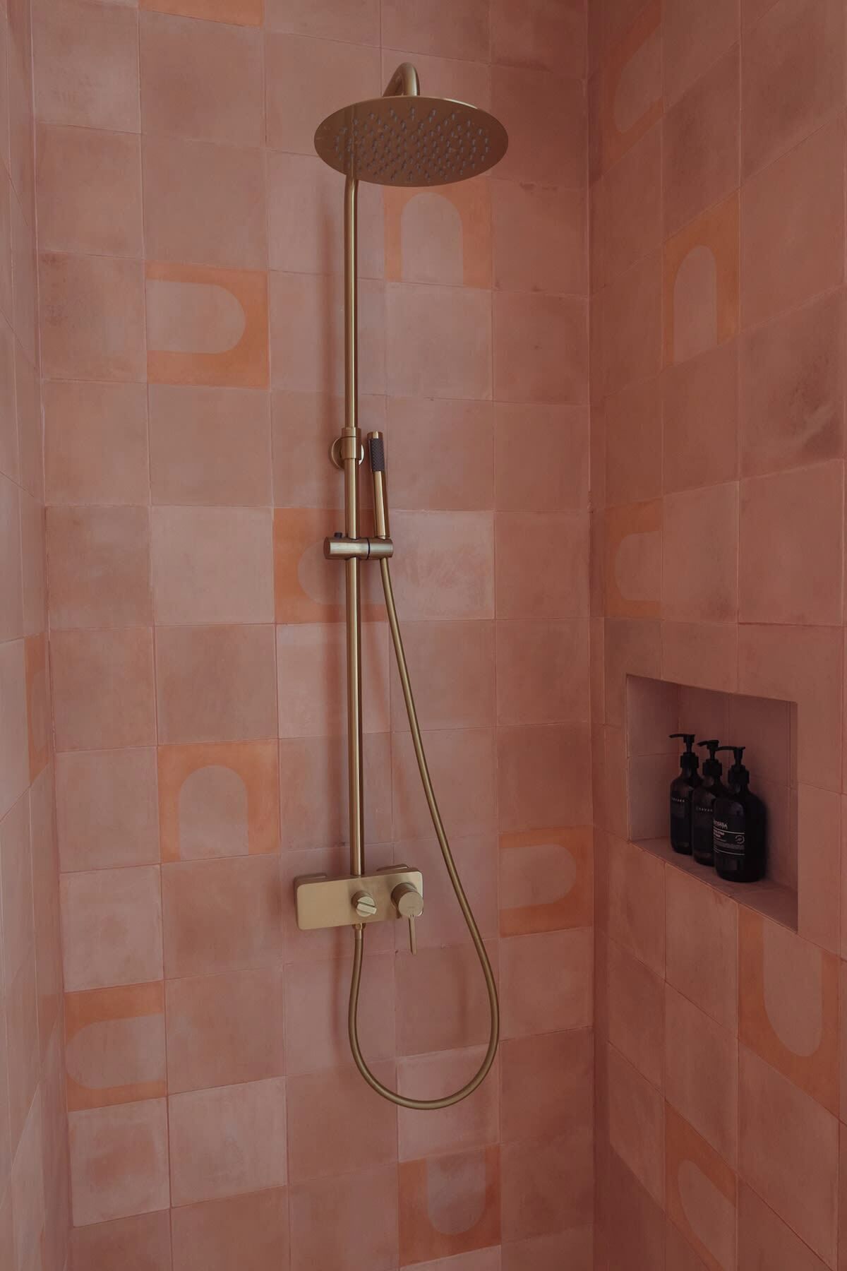 Eine Dusche mit Handbrause und Armaturen an der Wand.
