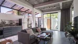 Ein modernes Wohnzimmer mit einer Couch, einem Couchtisch und einer Küchenzeile mit Arbeitsplatte und Schränken.