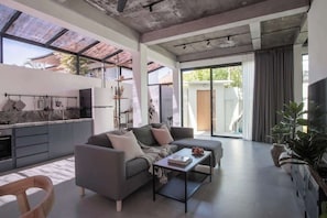 Ein modernes Wohnzimmer mit einer Couch, einem Couchtisch und einer Küchenzeile mit Arbeitsplatte und Schränken.
