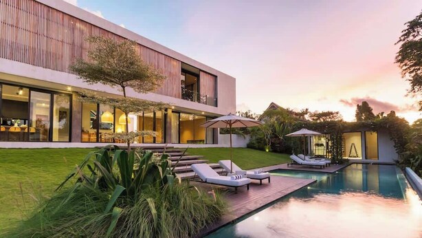 Ein modernes Haus mit Swimmingpool, Außenbereich und einem gepflegten Rasen.