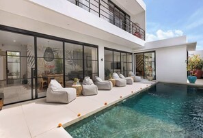 A modern house with a swimming pool, large glass windows, and outdoor seating. - PianoPiano Villas in Uluwatu. Breakfast included! (Pecatu)