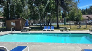 A swimming pool with lounge chairs and tables, surrounded by trees and a fenced area. - Downtown Pets Welcome Condo w/ Club Access (McCall)