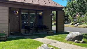 A building with a covered porch, outdoor seating, and hanging flower baskets. - Downtown Pets Welcome Condo w/ Club Access (McCall)