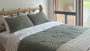 A bed with a wooden headboard, a window with a view, and a ceiling light fixture. - Downtown Pets Welcome Condo w/ Club Access (McCall)