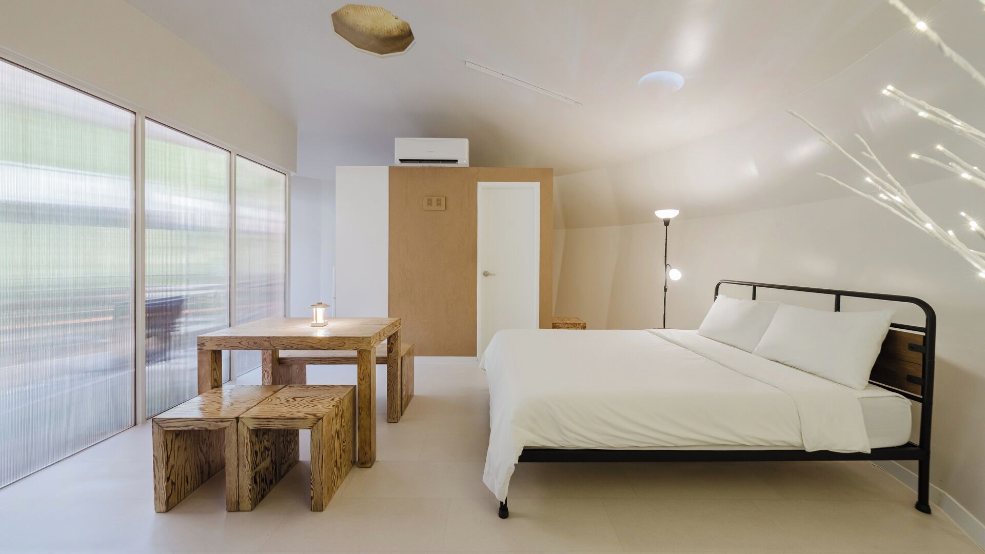 Une chambre moderne avec un lit, une table de chevet et une petite table en bois avec des chaises.