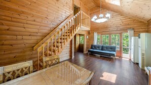 A wooden cabin interior with a staircase, a sofa, a dining table, and a refrigerator. - Gapyeong Pine4rest Glamping (Gapyeong)