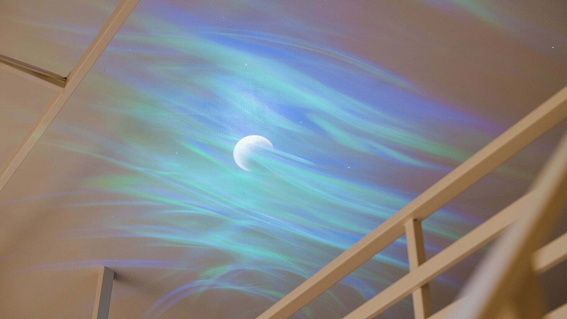 Eine Decke mit projiziertem Nordlicht und einem sichelförmigen Mond.