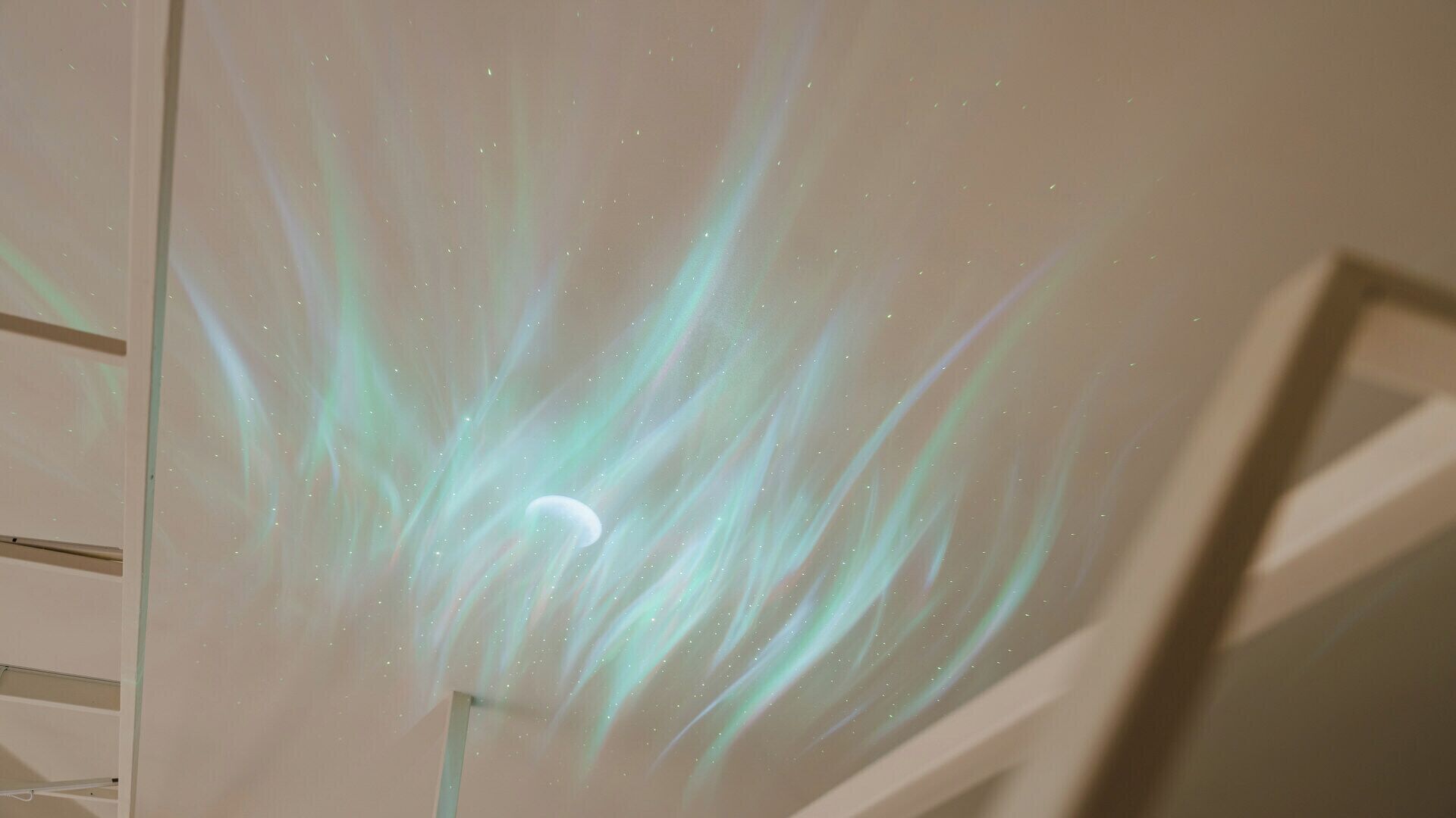 A projection of a starry sky with a crescent moon on a plain wall.
