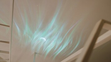 Proyección de un cielo estrellado con una luna creciente sobre una pared lisa.