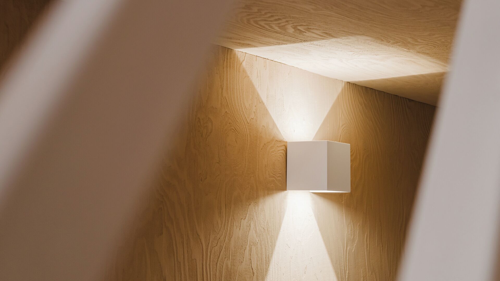 A modern interior with a wooden wall and a minimalist light fixture.