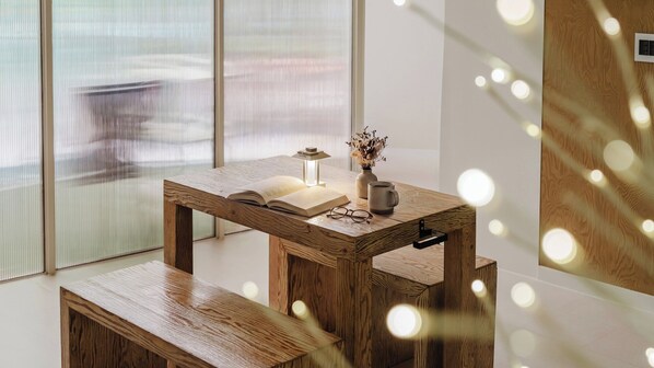A wooden desk with a book, glasses, and a mug, a vase with dried flowers, and a small table lamp. - Gapyeong Pine4rest Glamping (Gapyeong)