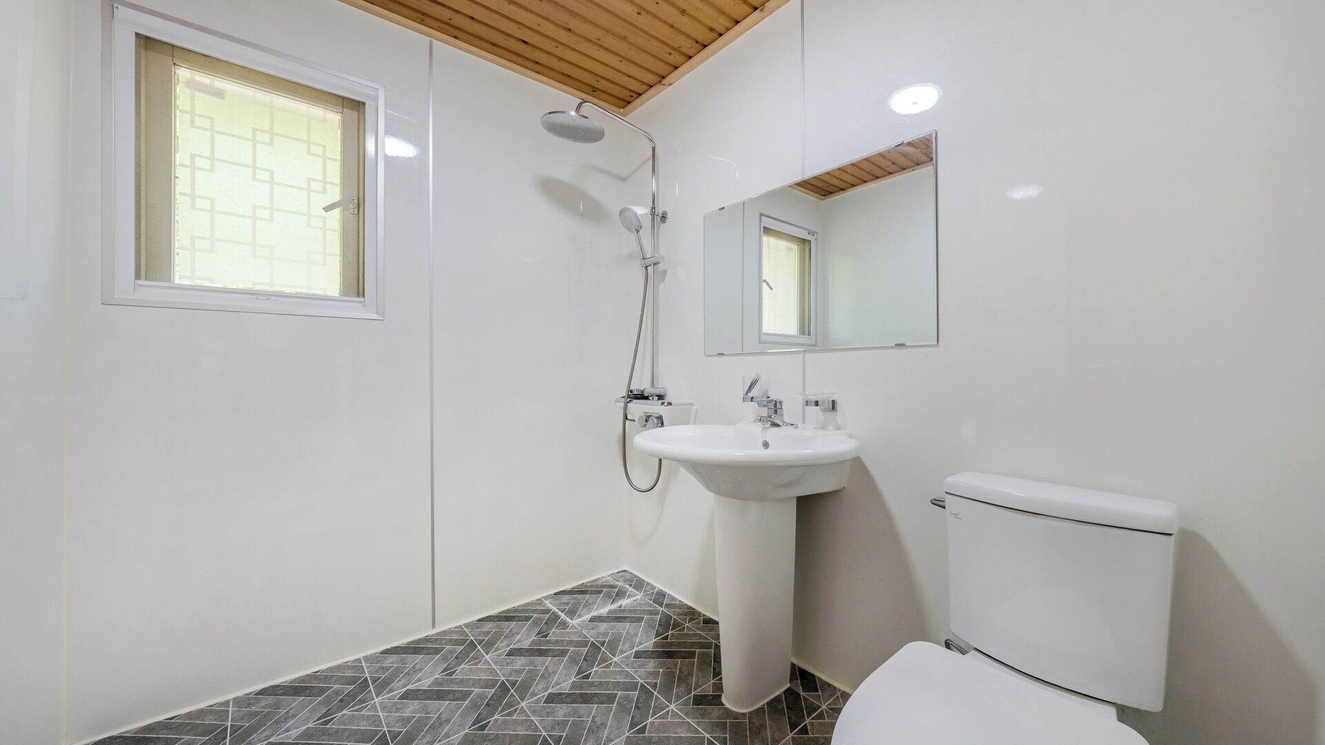 Un baño con ducha, lavabo, inodoro y ventana.