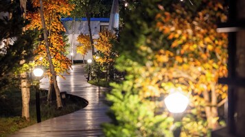 Un sendero conduce a un edificio con techo azul, rodeado de árboles con hojas otoñales.