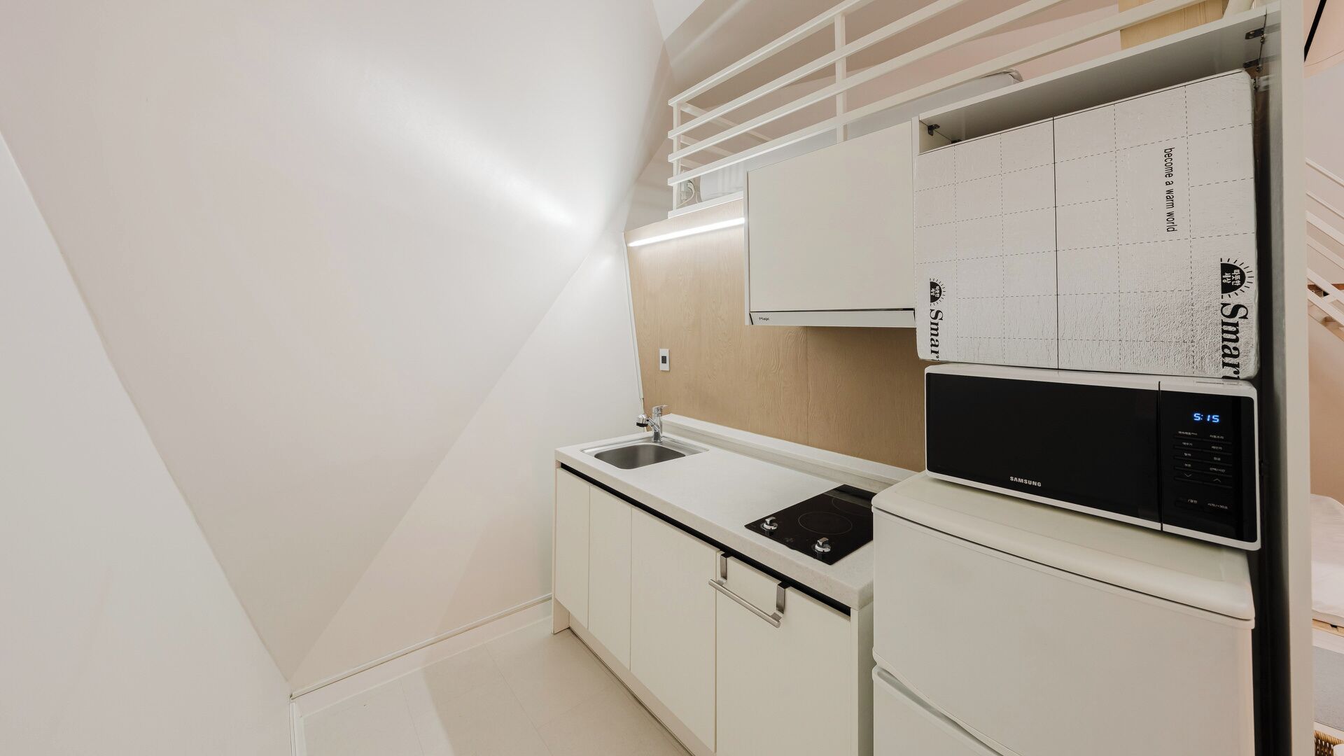 Una cocina moderna con un refrigerador Samsung integrado, un lavamanos y un calendario colgado en la pared.